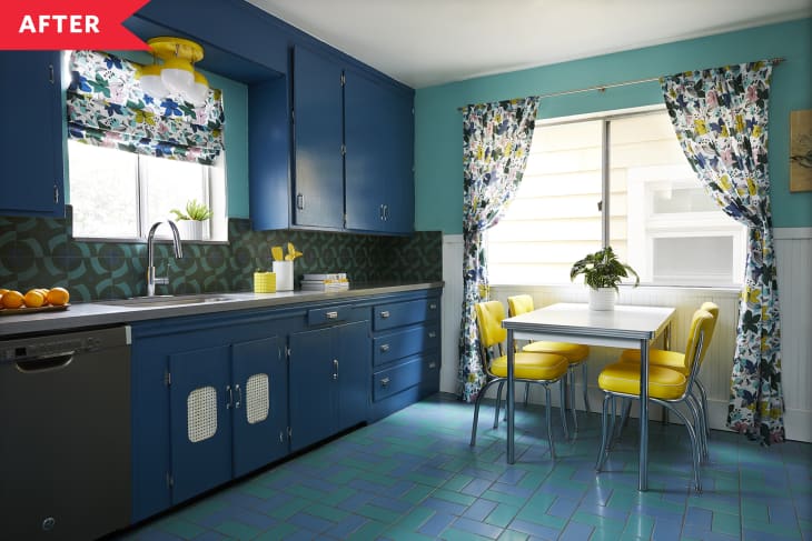 A kitchen with dark blue cabinets and blue tile floor with a small table in front of the window and four yellow chairs.