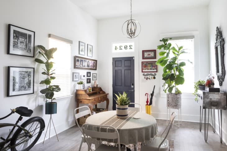 Dining room with round table, potted plants, wall art, bicycle, and a black door with house number 2924.