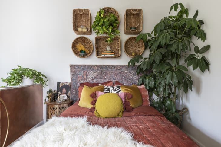A large potted tree next to a bed