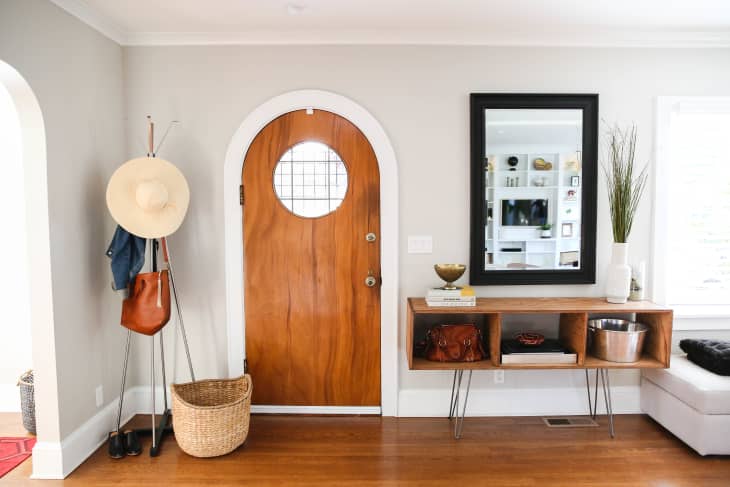 Entryway with arch-shaped door, coat rack, and mirror above credenza