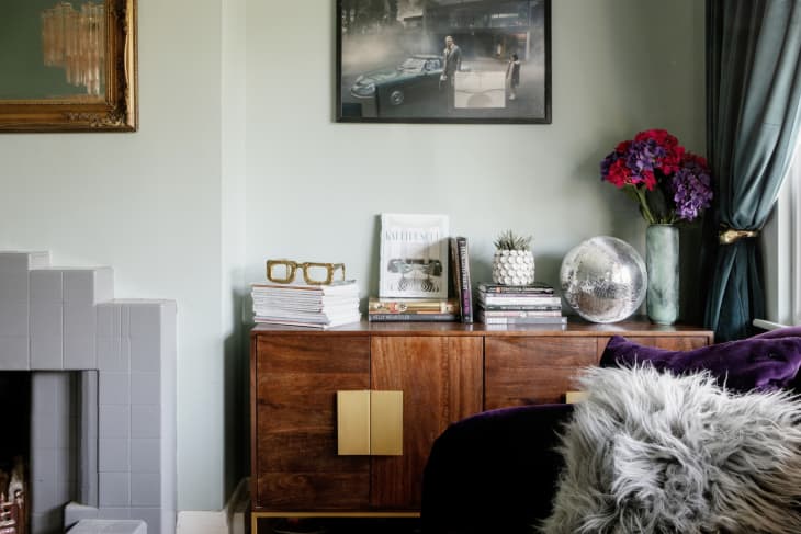 Living room credenza with books, disco ball, and vase of flowers on top