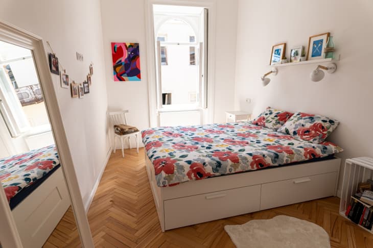 明亮的卧室，人字形木地板和花卉床上用品