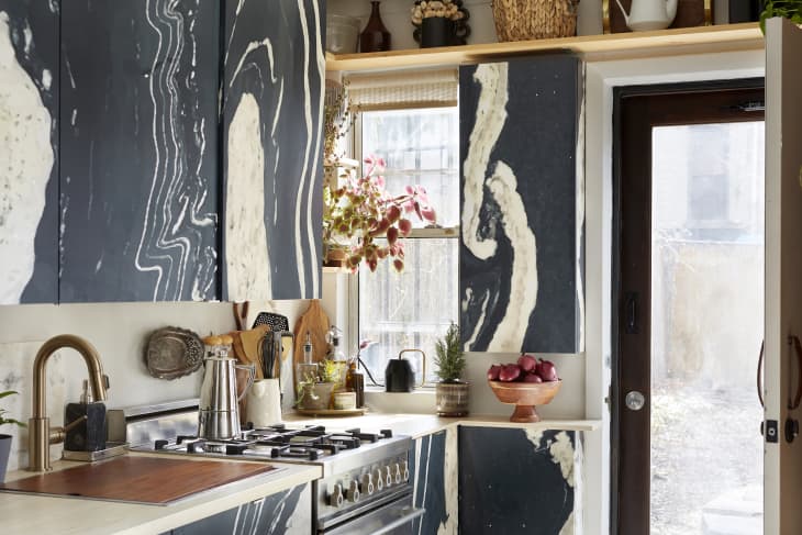 Kitchen with black and white painted cabinets, lots of light, plants, wood and gold accents