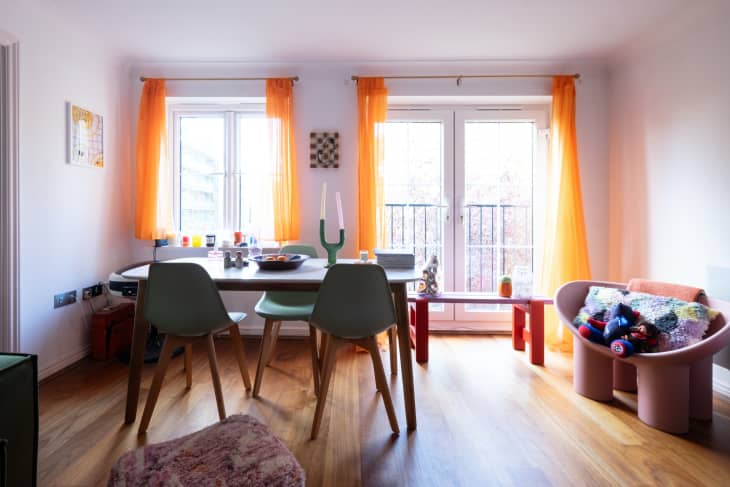 View of white dining area accented with orange curtains.