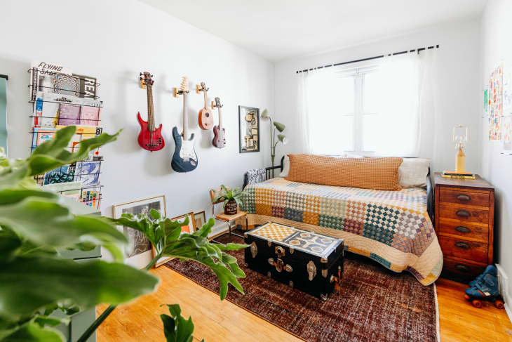 Guitars hang on wall of white room with daybed.