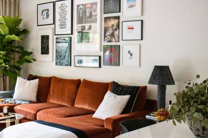 Art wall behind rust colored sofa in living room