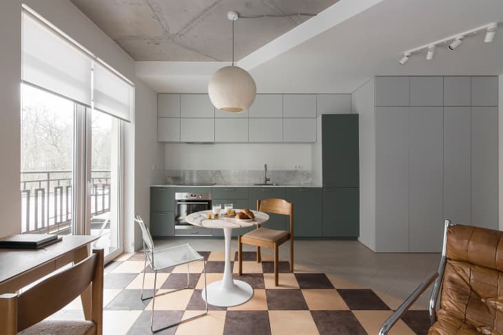 A round white dining table on a checkered floor between the living room and kitchen