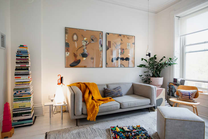 Large abstract paintings above grey sofa in light filled living room.