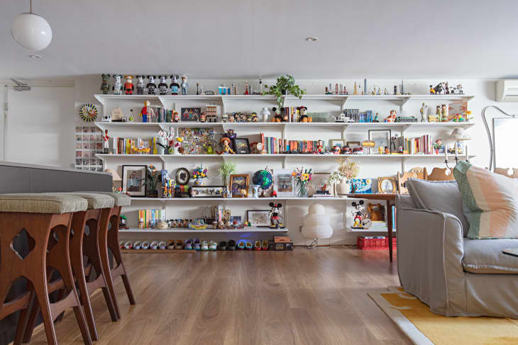 white living room with gray sofa and a full wall covered in shelves for books and art objects