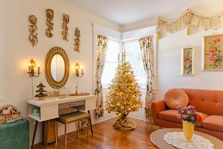 Living room generously decorated with colorful sparkly Christmas decor, tinsel, and trees