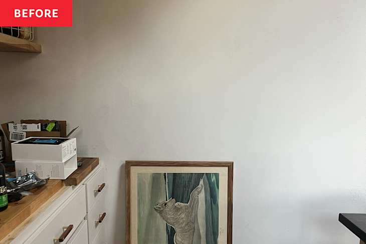 Cluttered kitchen corner with a framed artwork of a bear, boxes, and a wooden countertop.