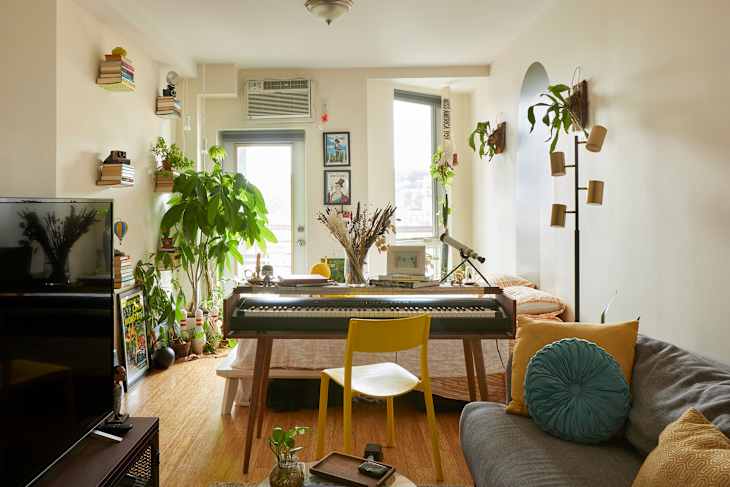 Main living area of studio apartment with colorful lamp and round mirror above couch.