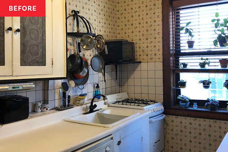 Small kitchen with white countertops, a sink, gas stove, hanging pots, and potted plants on window sill.