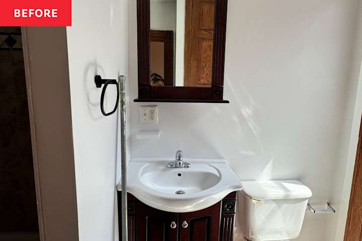 Small bathroom with a dark wood vanity, white sink, mirror, and toilet, featuring a towel ring on the wall.