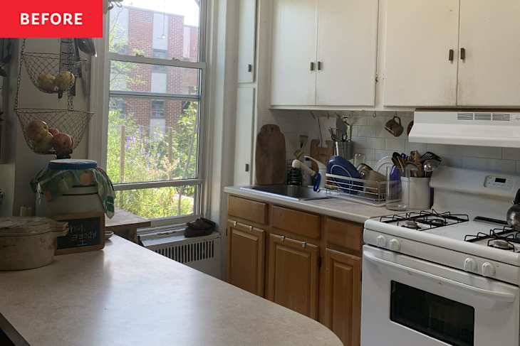Bright kitchen with wooden cabinets, a window view of greenery, and a countertop with a fruit basket and dish rack.