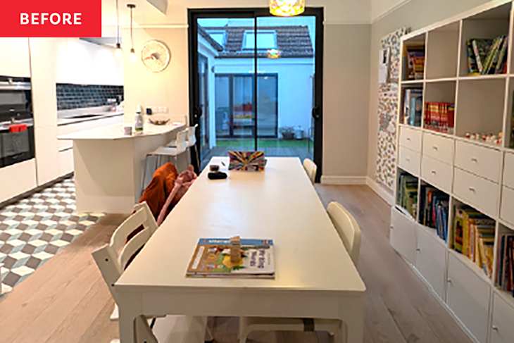 Bright kitchen and dining area with a white table, bookshelves, and sliding glass doors leading to a garden.