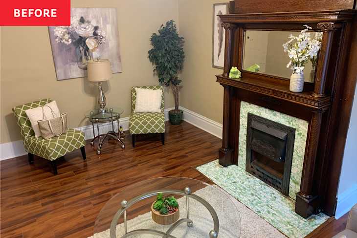 Cozy living room with green patterned chairs, glass table, lamp, and decorative fireplace with a mirror and flowers.