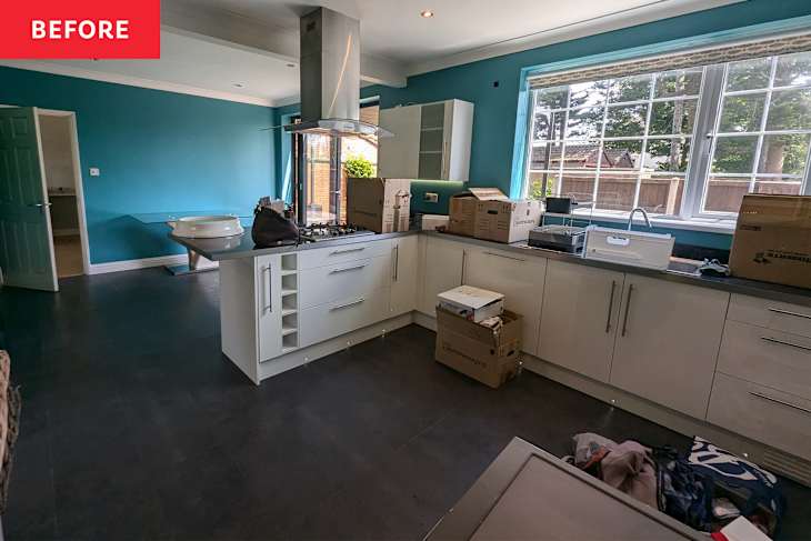 Modern kitchen with teal walls, white cabinets, a gas stove, and unpacked boxes scattered on the floor.