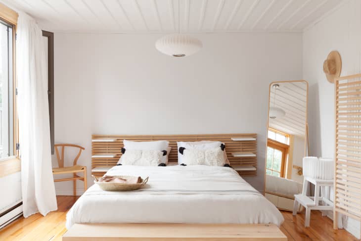 light wood tones are featured along with white bedding and walls in this Scandi minimalist bedroom
