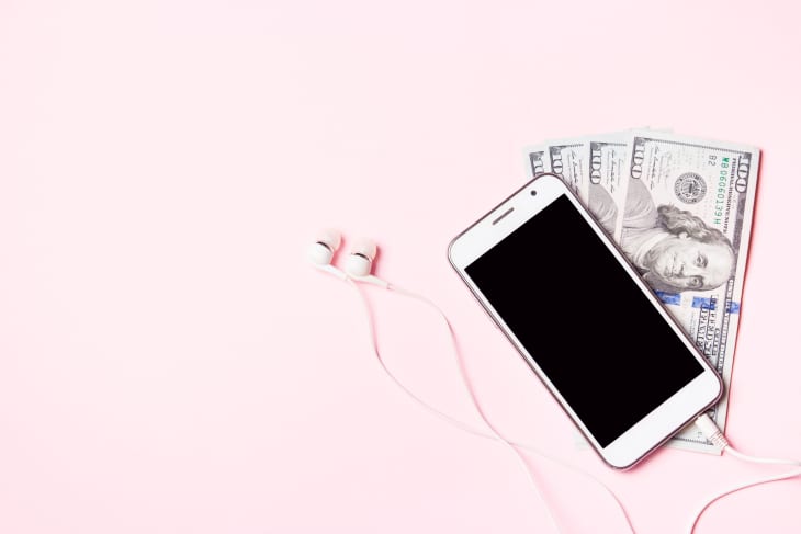 Mobile phone with headphones and money on pink background. Concept of payment and savings