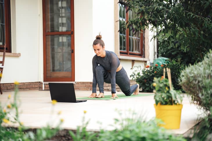 Fit young woman learning stretching exercise while watching video on laptop in backyard. High quality photo