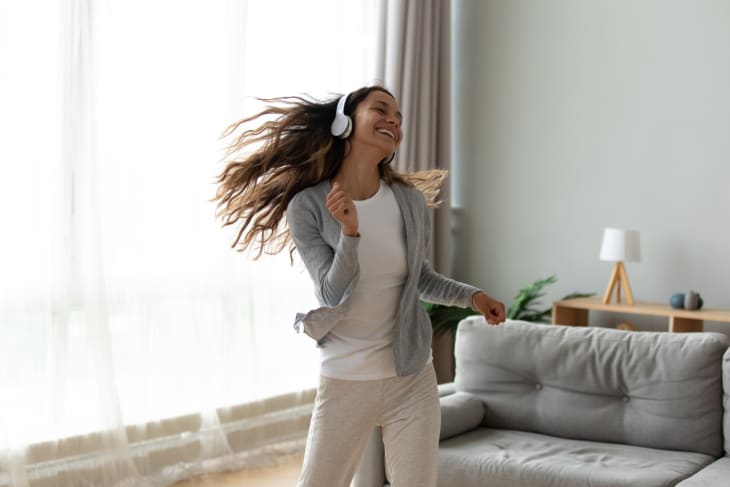 Woman wearing headphones dancing in living room