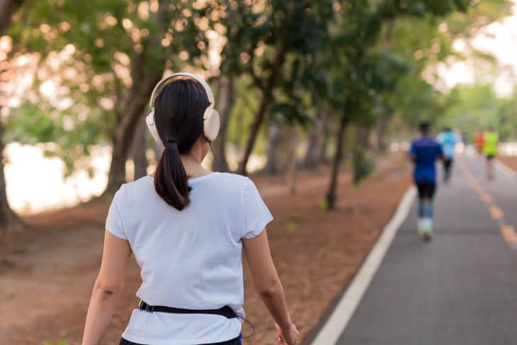 Woman wearing headphones walking on a trail