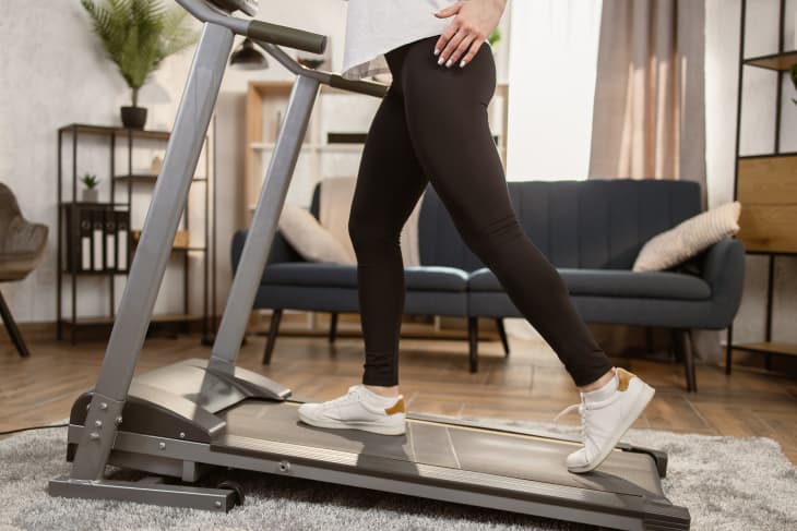 Woman walking on treadmill in living room at home