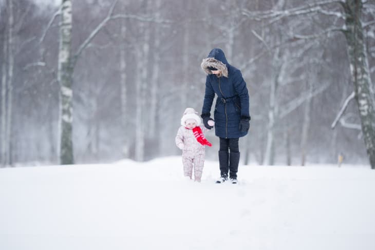 Mom walking with child wearing winter jackets in the snow