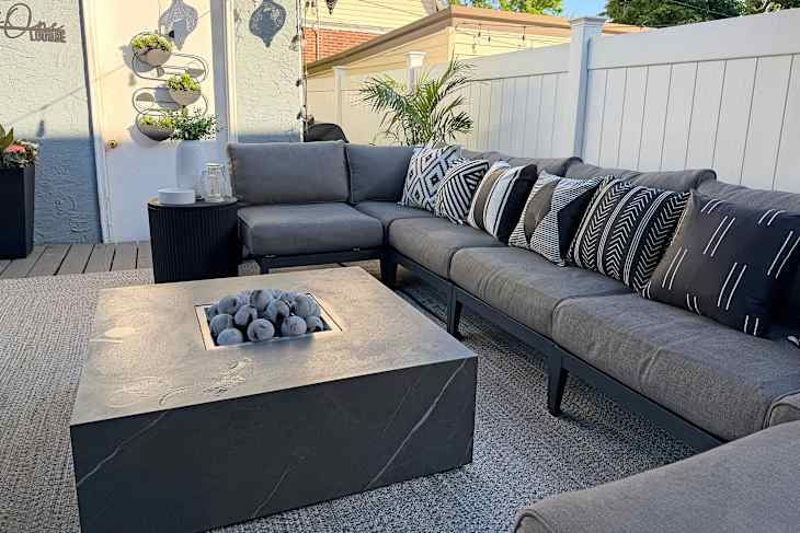 Grey sofa surrounding fire pit in outdoor space.