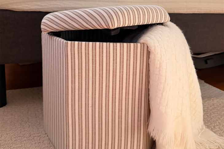 Blanket in striped IKEA storage pouf.