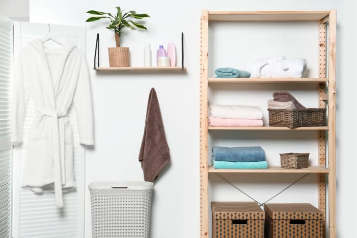 Clean towels and robe near white wall in modern bathroom interior