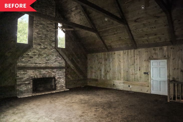 Spacious room with high wooden ceiling, brick fireplace, and two narrow windows.