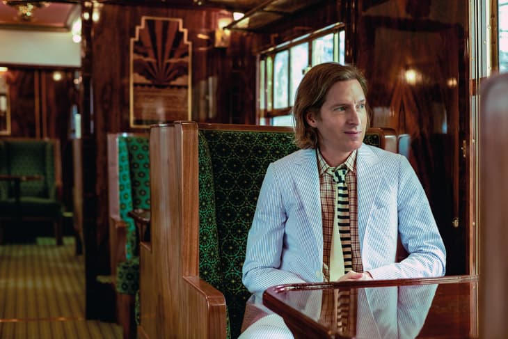 Wes Anderson sitting on green seat in train he designed