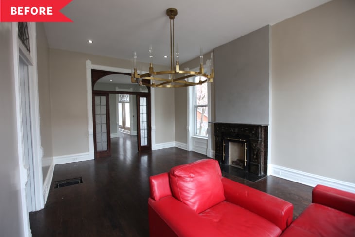 Living room with red sofa, dark wood floors, chandelier, and black fireplace.