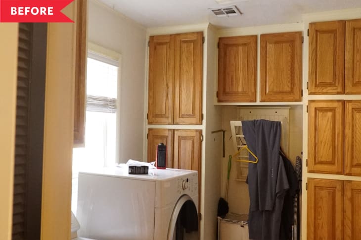 Laundry room with wooden cabinets, a white washing machine, and clothes hanging on a rack.