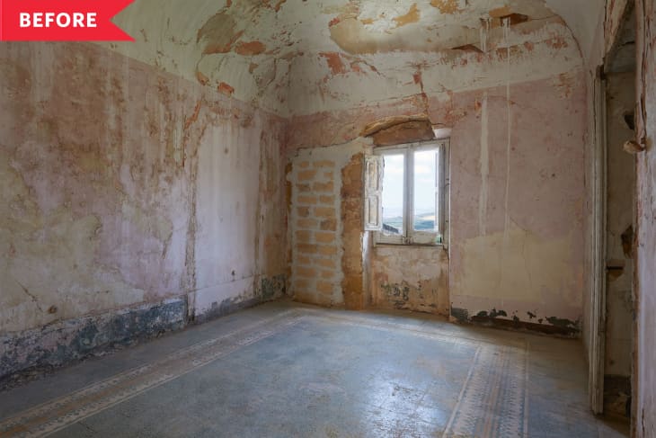 Empty room with peeling plaster walls, arched ceiling, and a single window with a view.