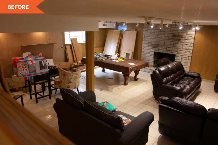 Basement with brown leather sofas, pool table, stone fireplace, and children's play area with toys and cardboard boxes.