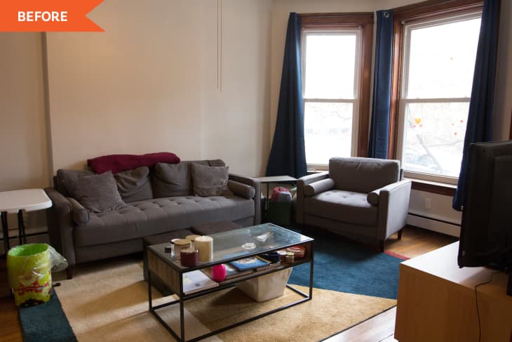 Living room with gray sofa, armchair, glass coffee table, and large windows with blue curtains.