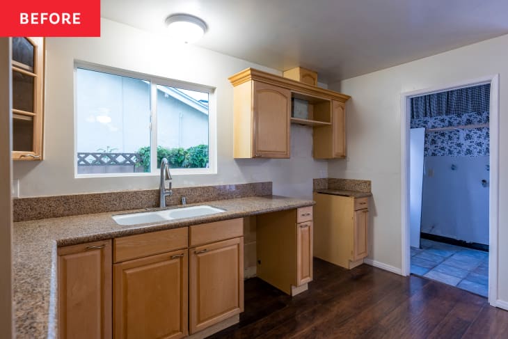 Empty kitchen with light wood cabinets, granite countertops, and a window above the sink.