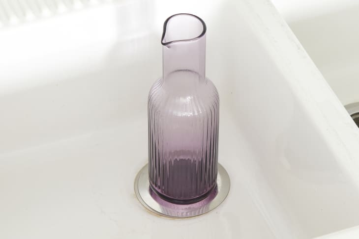 Angled view of a purple vase covering a sink drain.