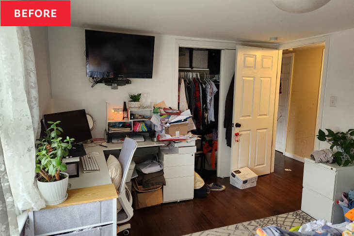 Cluttered home office with desk, computer, plants, and open closet filled with clothes and boxes.