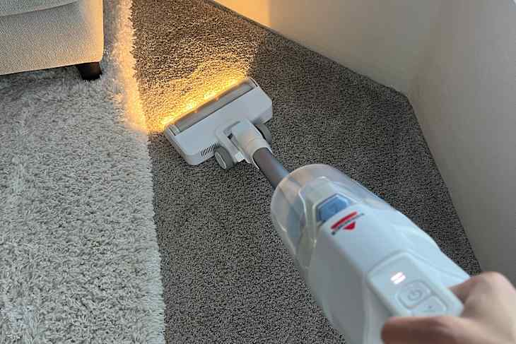 PowerClean Cordless Stick Vacuum in use on a carpeted surface.