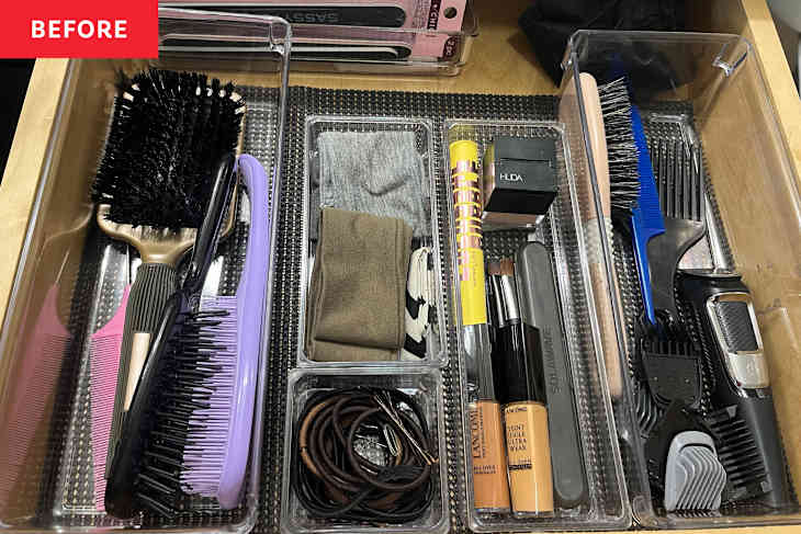 A drawer filled with hair tools, including brushes, combs, hair ties, and makeup products in clear organizers.