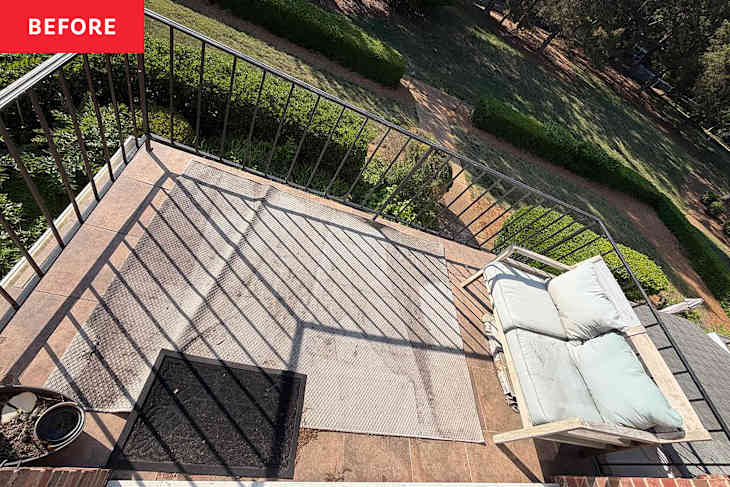 Balcony with a light-colored sofa, a textured rug, and a black doormat, surrounded by greenery and a railing.