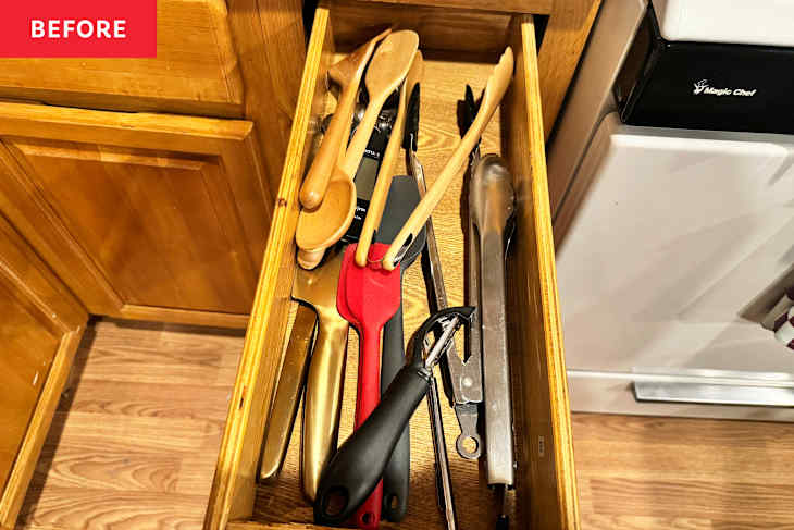 A wooden kitchen drawer filled with various cooking utensils, including spatulas, tongs, and a peeler.