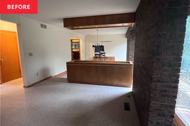 Living room before home staging. Mostly empty room with brown leather sofa, one exposed brick wall