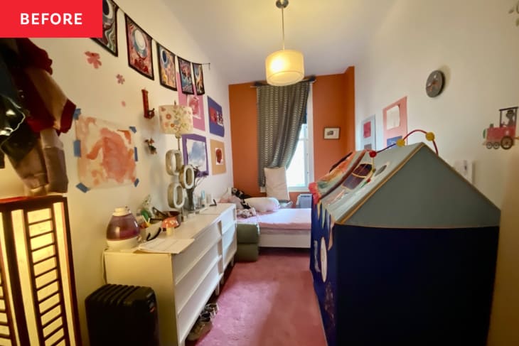 orange accent wall, pink carpet, alien poster banner, kids art on the walls, white dresser, knickknacks on dresser, play tent, twin bed against window, blue curtain, standing paper mache lamp