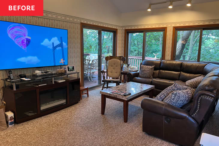 Wallpaper with border in light filled living room with large leather sectional.