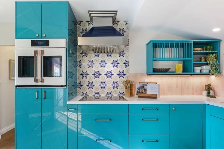 kitchen with bright turquoise cabinets and blue and white patterned wallpaper accents